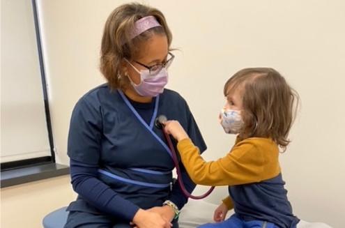 a young girl using a stethoscope on a pediatrician