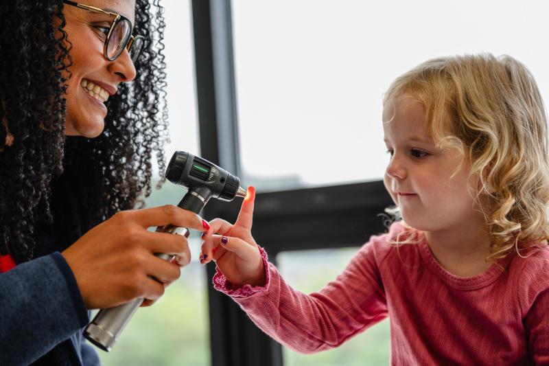 Physician and girl with otoscope